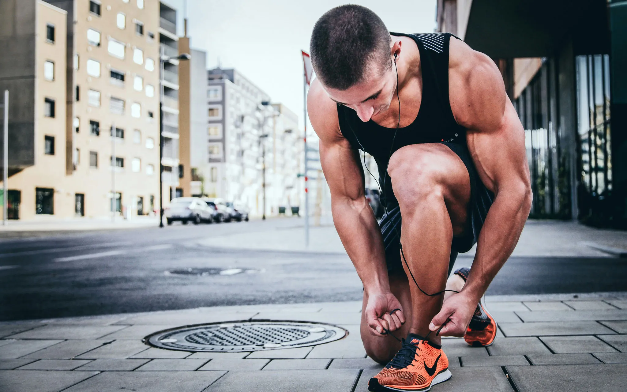 A man kneeling to tie his shoe in workout clothes